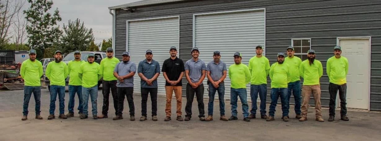 The GI Landscape crew — fourteen team members in branded uniforms, posed in front of the Canby yard