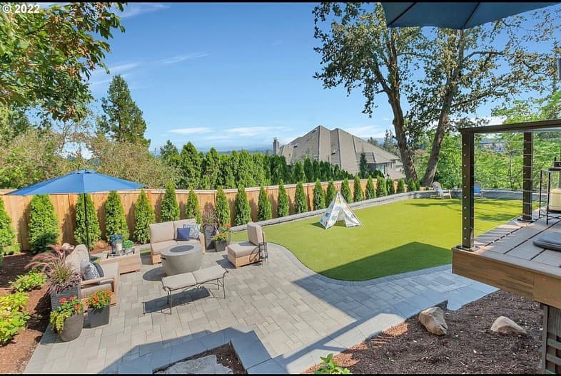 Aerial view of a finished GI Landscape backyard with paver patio, artificial turf, and cable-rail deck overlooking the Portland metro
