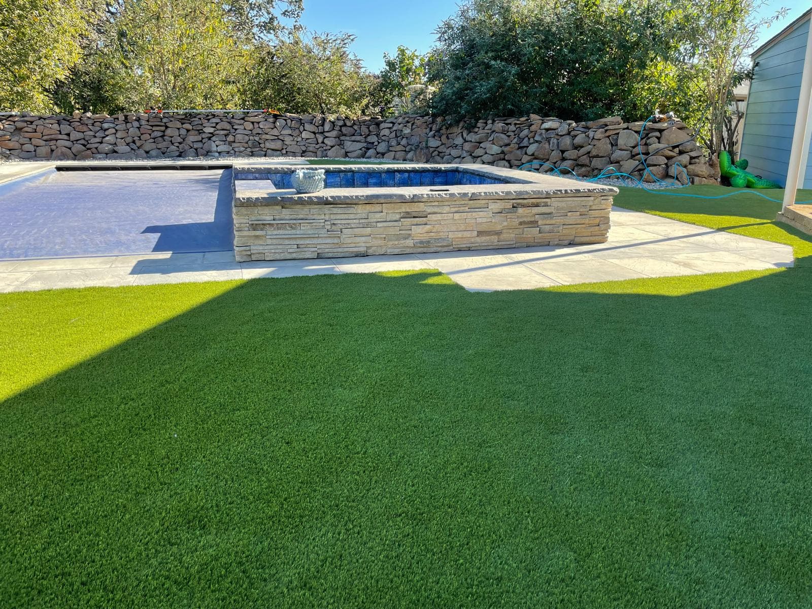 Backyard swimming pool surrounded by a paver deck and artificial turf — a GI Landscape multi-service build