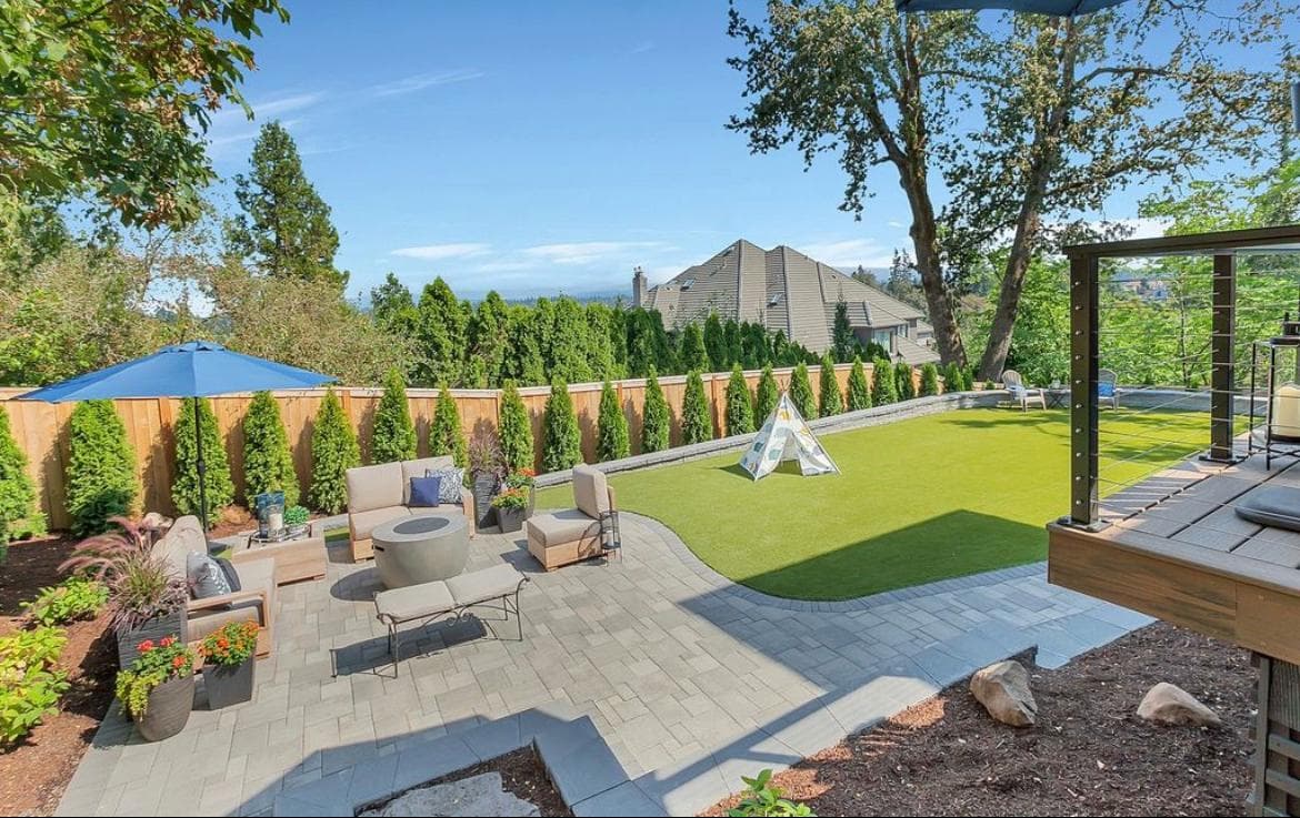Aerial view of a finished backyard with artificial turf, a paver patio, and a fire feature by GI Landscape