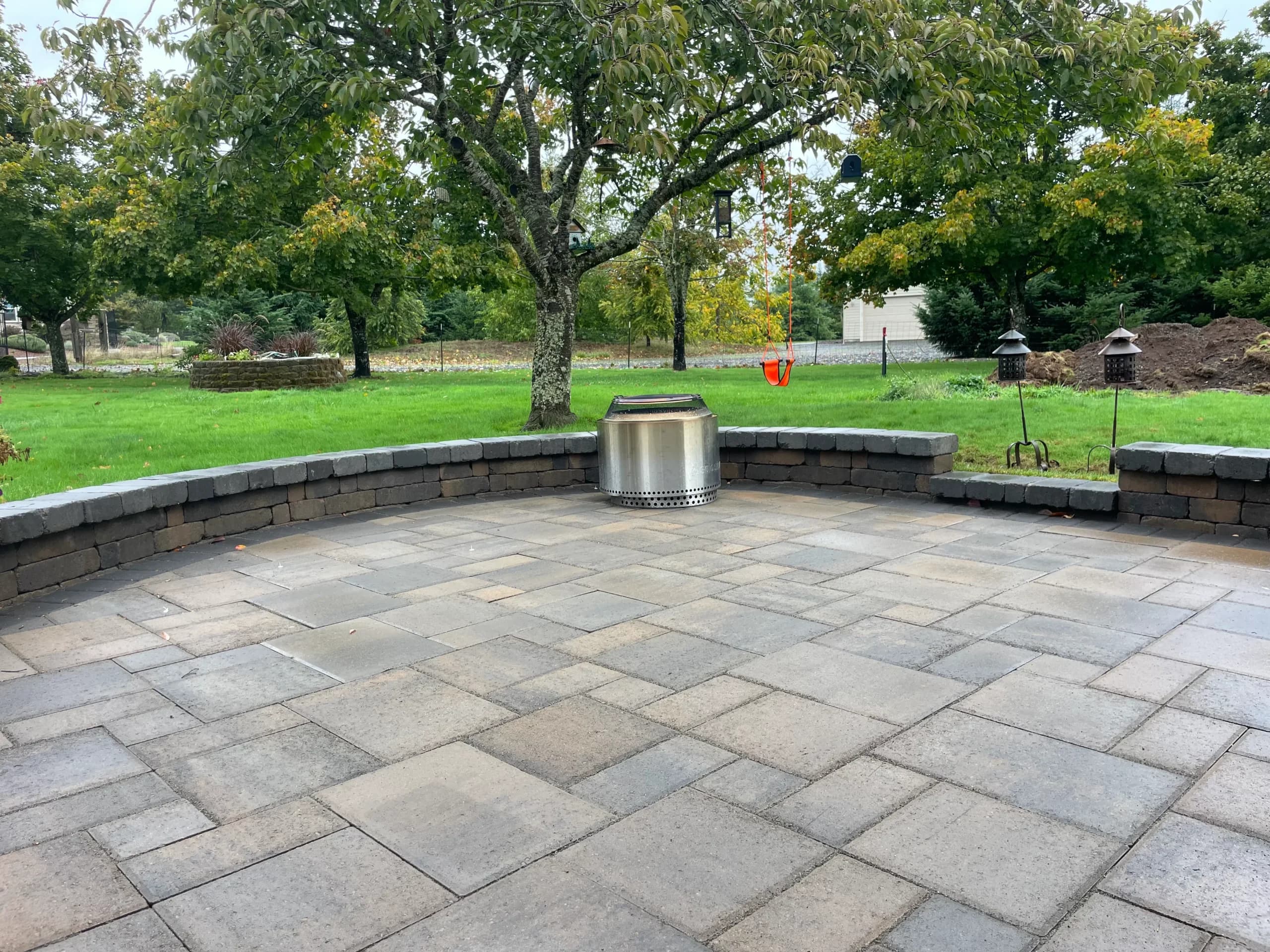 Circular paver patio with curved seat wall and stainless gas fire pit — GI Landscape